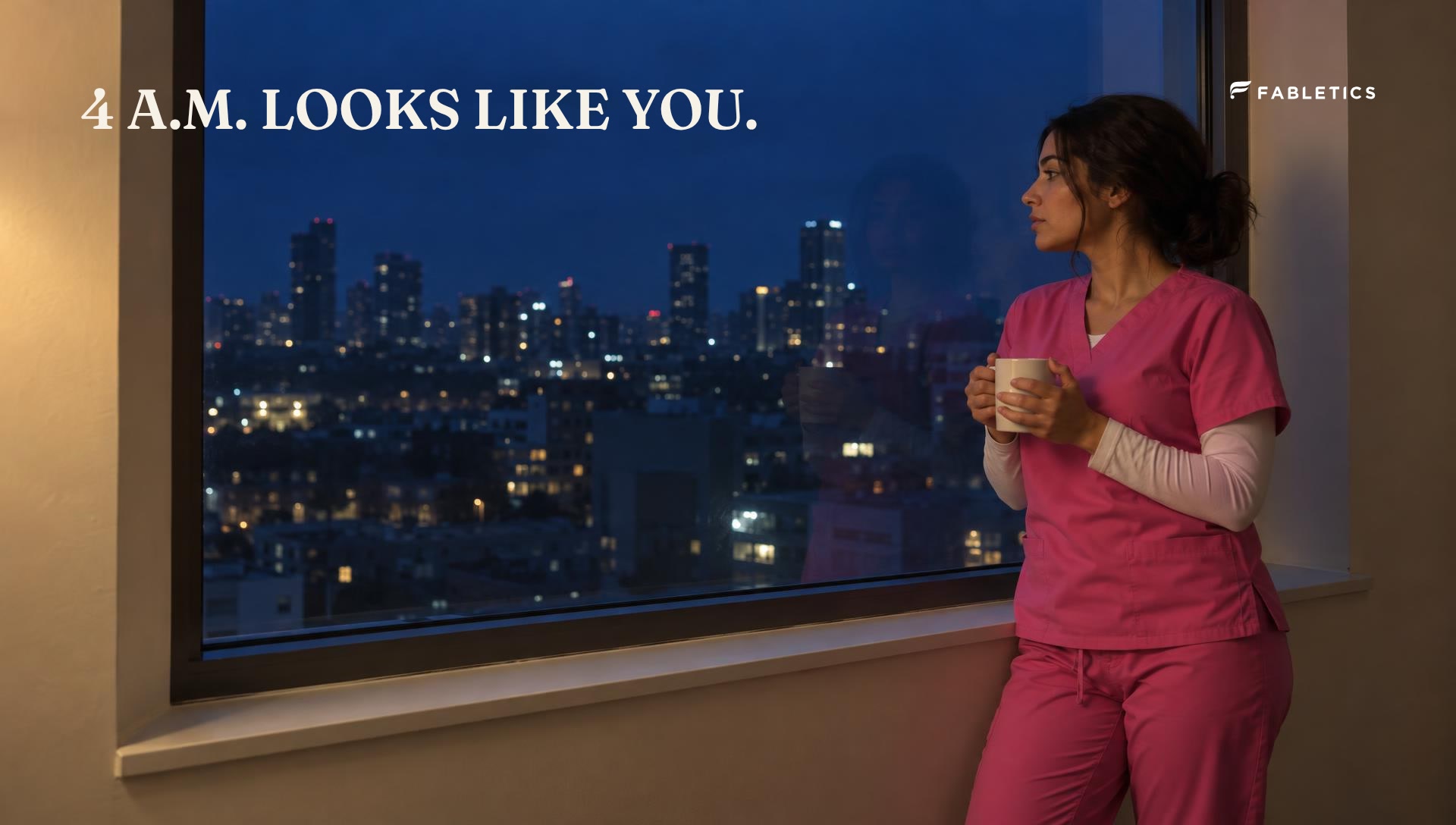 Woman in pink scrubs at a night window